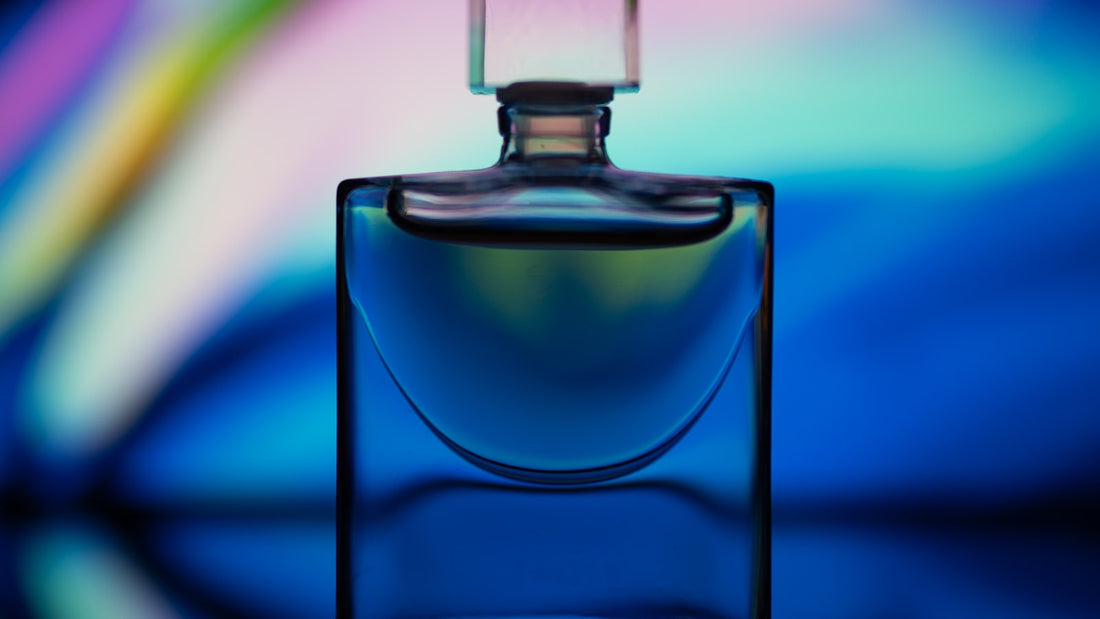 Clear glass perfume bottle bathed in soft pink light, suggesting a feminine floral fragrance