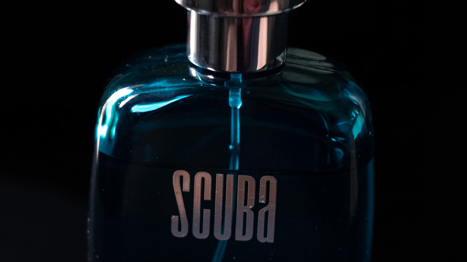 Dark, moody photograph of a perfume bottle on a black surface, evoking masculine fragrance